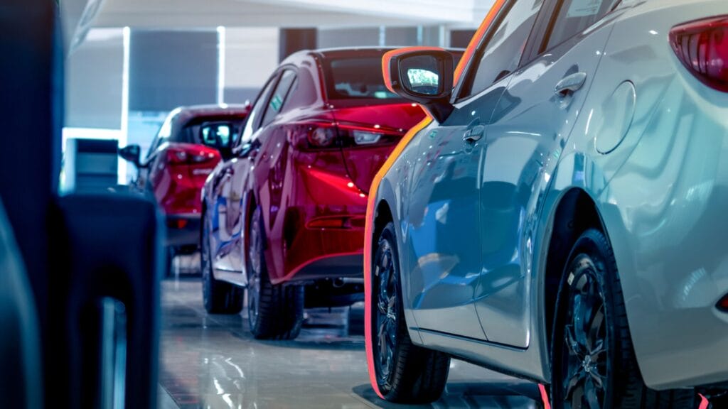 Row of modern passenger cars in a showroom, with glossy red and blue finishes, symbolizing the evolution of connected and software-defined vehicles and the demand for accurate multilingual communication.