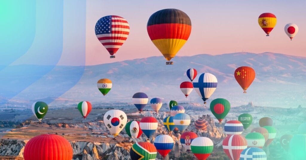 Dozens of hot air balloons displaying world flags including USA, Germany, India, and China floating over a rocky landscape at sunrise