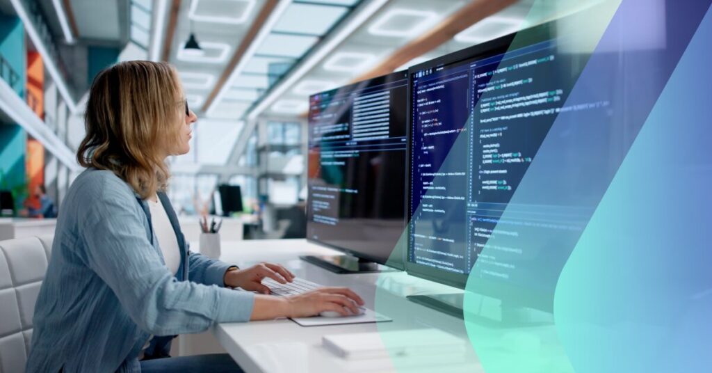 Developer working at a dual-monitor desk setup with code displayed on screen.